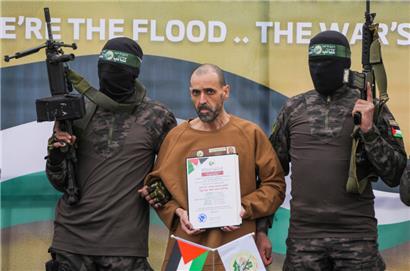 Der israelische Gefangene Eli Sharabi (M), der seit dem 7. Oktober 2023 von der Hamas im Gazastreifen als Geisel gehalten wird, wird von Hamas-Kämpfern eskortiert, bevor er dem Roten Kreuz im zentralen Gazastreifen übergeben wird
