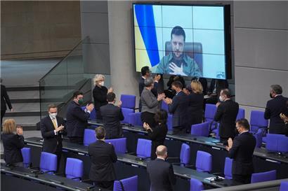 Der ukrainische Präsident Wolodymyr Selenskyj spricht auf einer Videoleinwand im Bundestag und bekommt Applaus von der Bundesregierung

