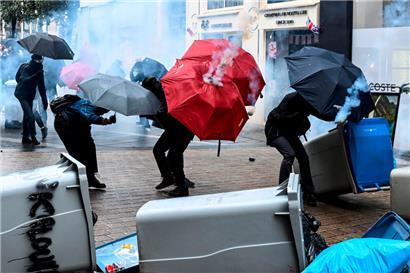 Des manifestants utilisent des parapluies pour se protéger des tirs de gaz lacrymogène
