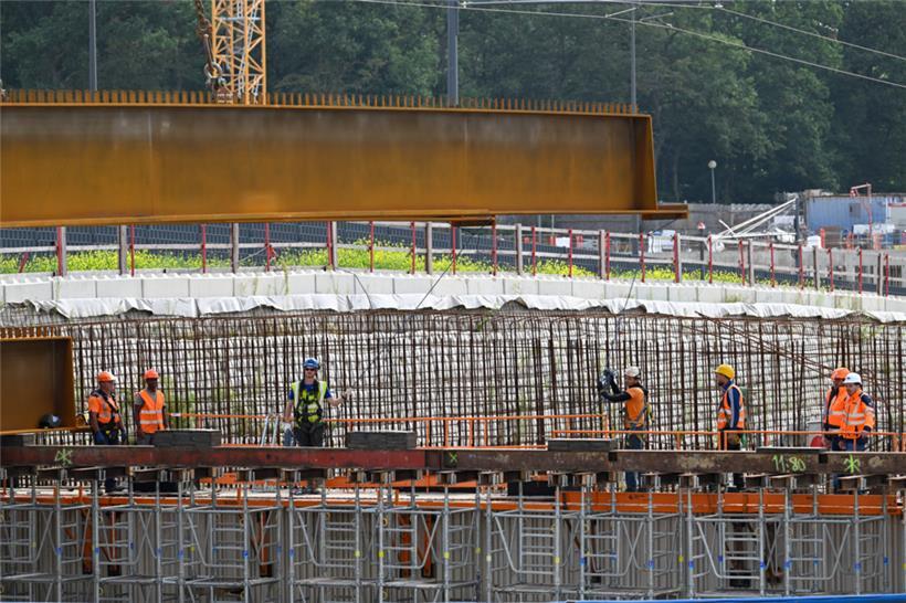 Die Arbeiter bringen den am Kran befestigten Stahlträger langsam in Position