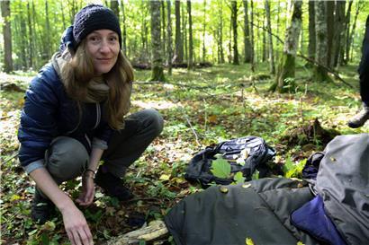 Die Helferin Maria Zlonkiewicz kniet in einem Wald bei Hajnowka nahe der polnisch-belarussischen Grenze neben Gegenständen, die wahrscheinlich von Flüchtlingen aus dem Nahen Osten zurückgelassen wurden
