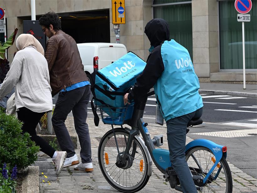 Wolt-Kuriere auf Motorrollern und Leihfahrrädern liefern Essen in der Stadt, repräsentativ für den Covid-Lieferdienst-Trend