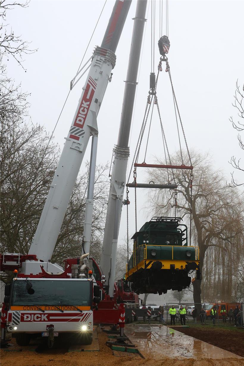 Zwei Kräne positionieren eine Lokomotive präzise auf den Gleisen bei einem Eisenbahnbaustellen-Einsatz