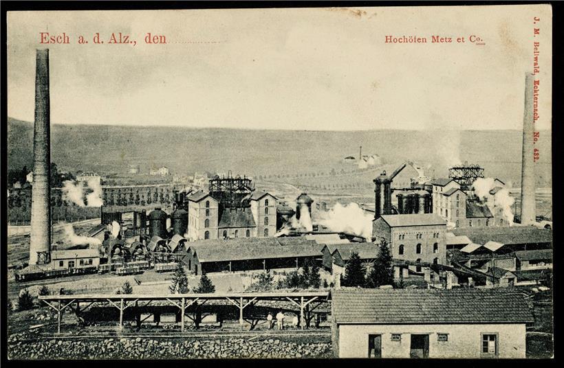 Die Metzeschmelz um 1900. Im Vordergrund sieht man die mit Eisenerz gefüllten Buggys, die vom Lallingerberg kommen und über Brücken zu den Hochöfen geführt werden; dahinter die Gleise, die die Fabrik versorgten. Die Reihe der Hochöfen mit Cowper, Schornsteinen und Gießhallen rundet das Bild ab. Hinter dem Werk rechts die Brauerei Buchholtz in Lallingen. Hinter…
