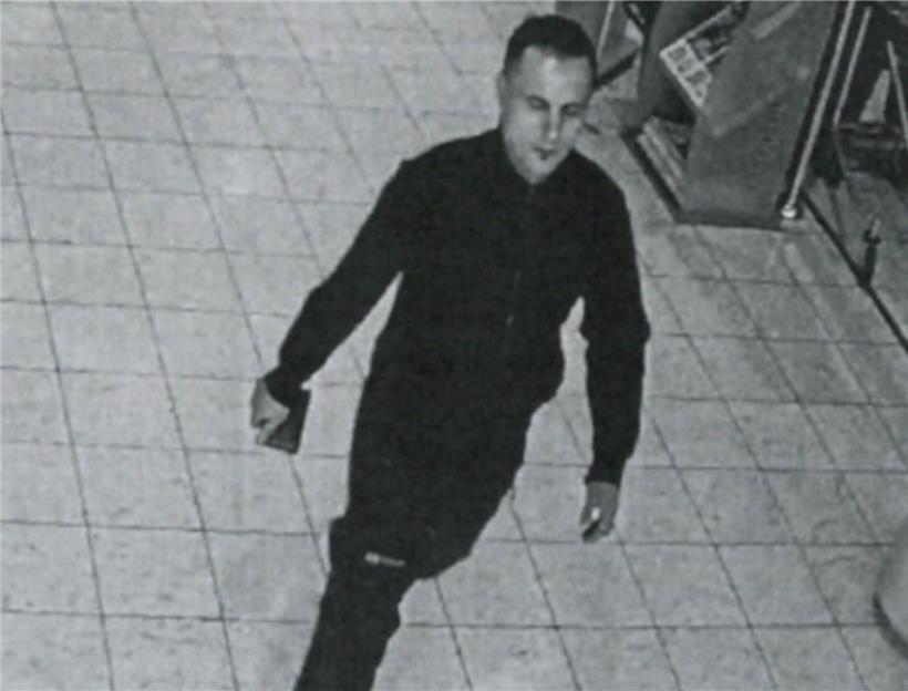 Polizeiliches Fahndungsbild einer gesuchten Person, Gesicht frontal, helle Haut, kurze dunkle Haare, neutrale Mimik