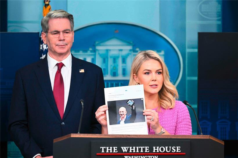 Die Pressesprecherin des Weißen Hauses, Karoline Leavitt, begleitete von US-Finanzminister Scott Bessent, hält einen Nachrichtenartikel über Amazon-CEO Jeff Bezos
