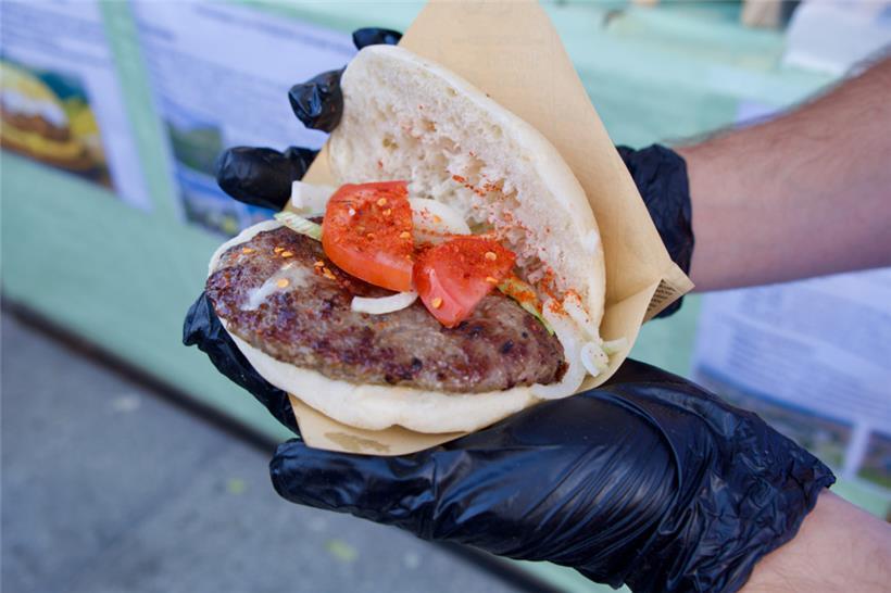 Die Sharska Pljeskavica, ein gefüllter Fleischburger mit Käse, wird am Kosovo-Stand frisch gegrillt und traditionell serviert
