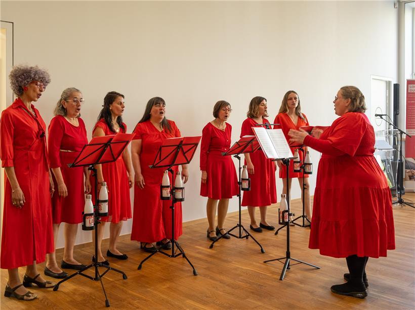 Singing Red Ladies singen live bei Veranstaltung, Frauenchor in roten Outfits auf Bühne
