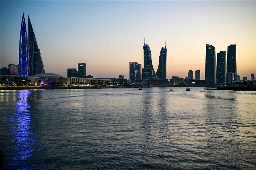 Skyline von Manama, Bahrain bei Sonnenuntergang mit Entsalzungsanlage im Vordergrund, Symbol für Wasserversorgung in der Region
