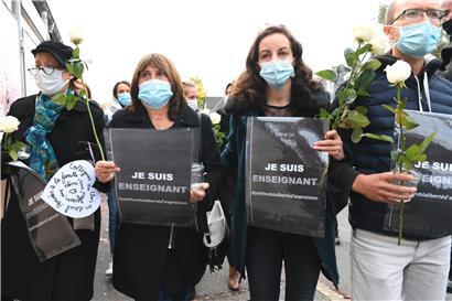 Die Teilnehmer einer Kundgebung vor einer Mittelschule halten nach einer brutalen Messerattacke Rosen und Schilder mit der Aufschrift „Ich bin Lehrer – ich verteidige die Meinungsfreiheit“. Nach der mörderischen Attacke auf einen Lehrer bei Paris sind fünf weitere Menschen festgenommen worden. Der mutmaßliche Täter war kurz nach der Tat von der Polizei getötet worden.
