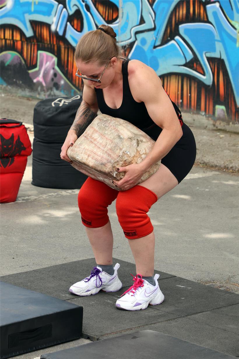 Teilnehmer heben schwere Steine bei einem Kraft- und Ausdauertraining im Outdoor-Fitness-Event