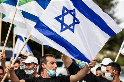 Die Teilnehmer von verschiedenen politischen Gruppen schwenken israelische Flaggen, während sie gegen die Bildung der neuen israelischen Regierung protestieren
