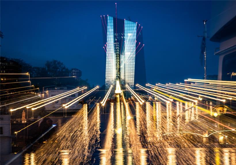 Die Zentrale der Europäischen Zentralbank (EZB) reflektiert das letzte Abendlicht über den illuminierten Mainbrücken
