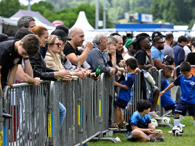 Zuschauer verfolgen gespannt ein Sportereignis vom Spielfeldrand aus, mit intensiver Atmosphäre und Teamunterstützung