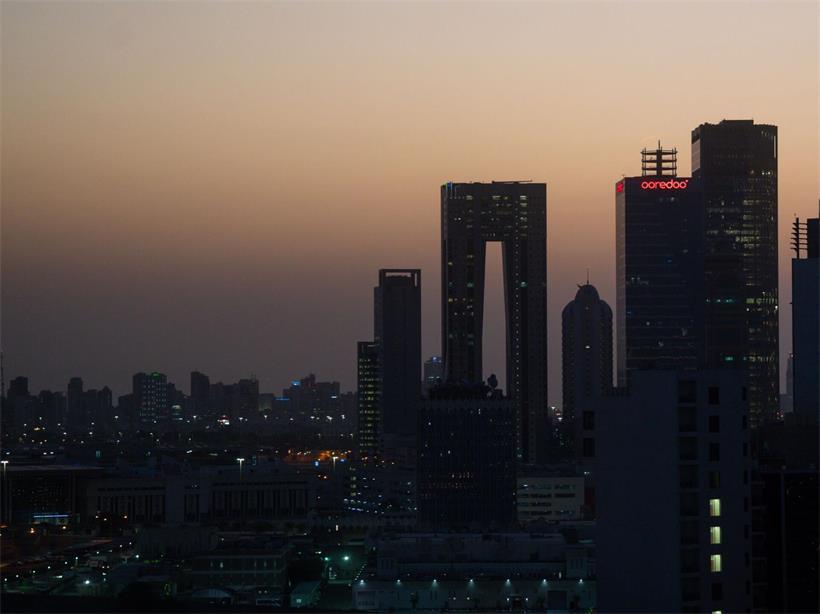 Die aufgehende Sonne färbt den Himmel hinter der Skyline von Kuwait-City rötlich