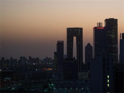 Die aufgehende Sonne färbt den Himmel hinter der Skyline von Kuwait-City rötlich