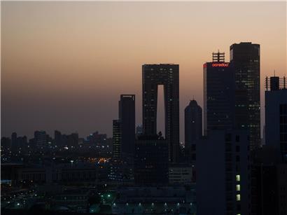 Die aufgehende Sonne färbt den Himmel hinter der Skyline von Kuwait-City rötlich