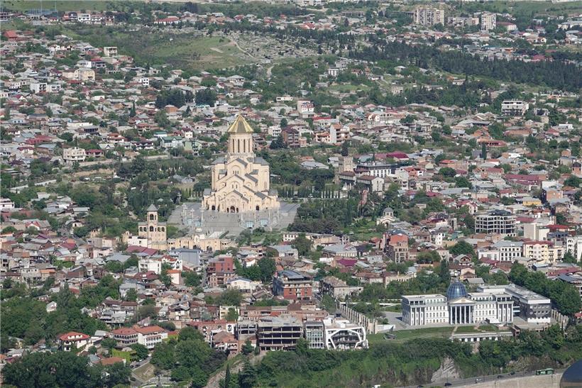 Panoramablick auf die georgische Hauptstadt Tiflis mit historischen Gebäuden und moderner Stadtlandschaft bei Sonnenuntergang