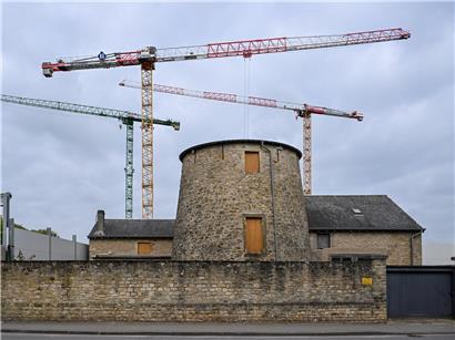 Historische Windmühle neben moderner Krankenhaus-Baustelle im ländlichen Baugebiet