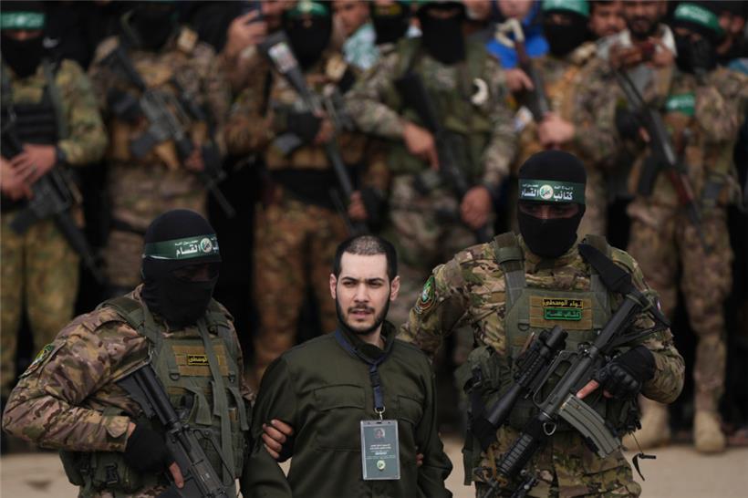 Die israelische Geisel Elija Cohen (M) wird von vermummten und bewaffneten Mitgliedern der Terrororganisation Hamas in Nuseirat im zentralen Gazastreifen eskortiert, bevor sie dem Internationalen Roten Kreuz (IKRK) übergeben wird
