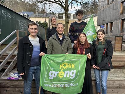 Junge Menschen beim politischen Treffen der Déi jonk Gréng mit grünen Bannern und engagierter Diskussion