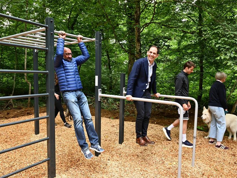 Läufer und Spaziergänger nutzen neue Outdoor-Stationen für zusätzliche Fitness-Übungen im Park