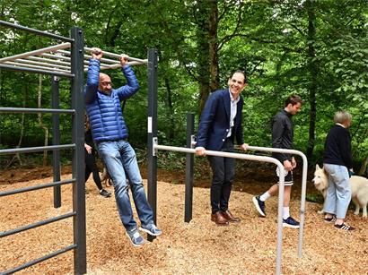 Läufer und Spaziergänger nutzen neue Outdoor-Stationen für zusätzliche Fitness-Übungen im Park