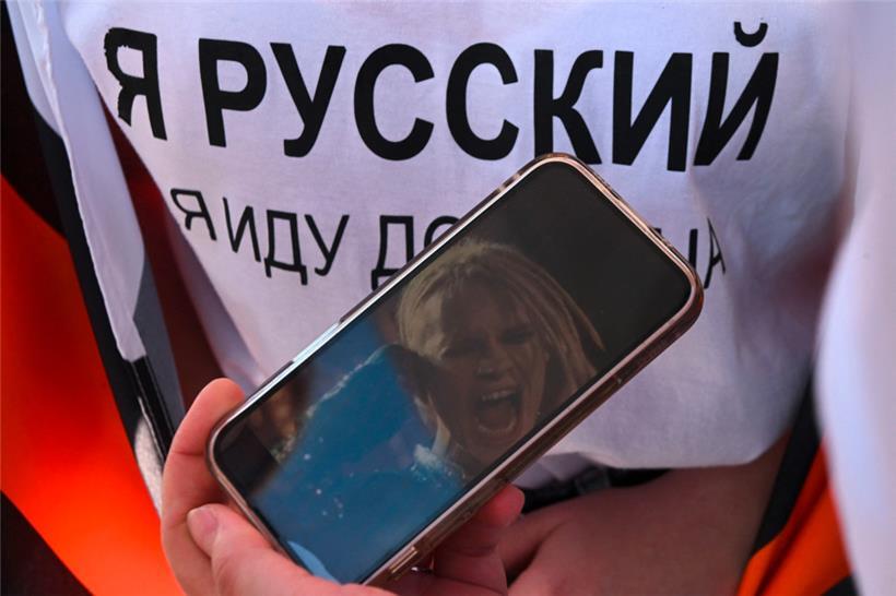 Die russische Propaganda hat längst die Pop-Kultur im Land vereinnahmt: „Ich bin Russin“ steht auf dem T-Shirt einer Frau, die auf ihrem Handy ein Bild des russischen Sängers „Shaman“ zeigt, der bei vom Kreml organisierten Veranstaltungen auftritt
