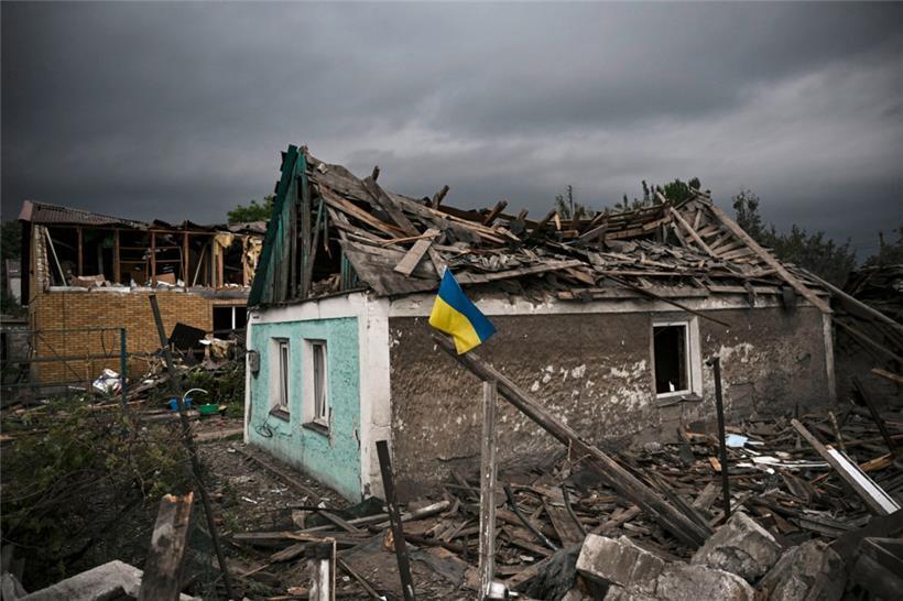 Die ukrainische Fahne weht vor einem zerstörten Haus im Donbass
