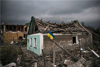 Die ukrainische Fahne weht vor einem zerstörten Haus im Donbass
