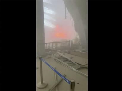 Passagierterminal des internationalen Flughafens Kuwait nach Drohnenangriff, zerstörte Gebäude und Rauchwolken sichtbar