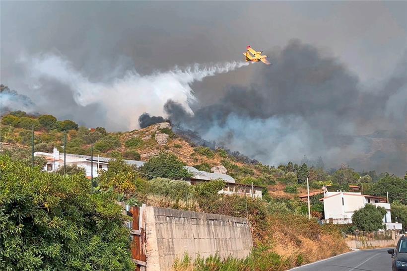 Dieses Foto vom 26. Juli zeigt ein Canadair-Löschflugzeug, das während eines Brandes in der Nähe von Häusern im Stadtteil Tono in Messina, Sizilien, Wasser abwirft
