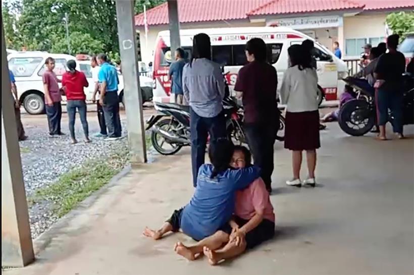 Dieses Videostandbild zeigt eine Frau, die vor dem Tatort eines Angriffs auf eine Kindertagesstätte auf dem Boden sitzt und eine andere Person umarmt. Ein ehemaliger Polizeibeamter hat in einer Kindertagesstätte in Thailand ein Blutbad angerichtet und mehr als 30 Menschen getötet. 
