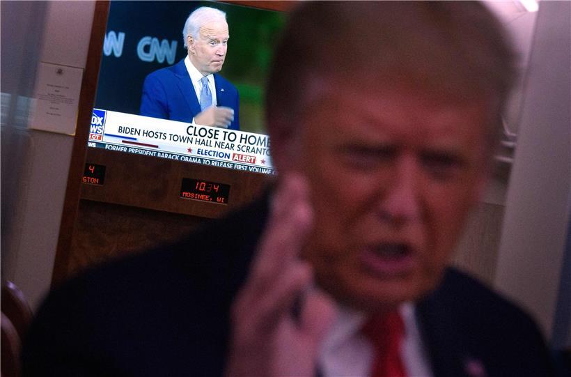 Donald Trump spricht mit Journalisten, im Hintergrund ist Joe Biden im TV zu sehen – der demokratische Herausforderer geht als Favorit in die drei letzten Wahlkampfwochen
