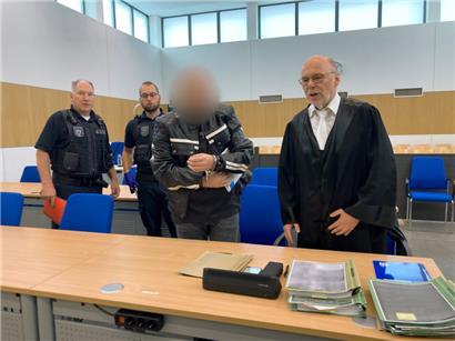 Ein 44-Jähriger (2.v.r.), der vom Fahrrad aus Passanten mit Steinen beworfen und teils schwer verletzt haben soll, kommt zu Prozessbeginn in den Gerichtssaal
