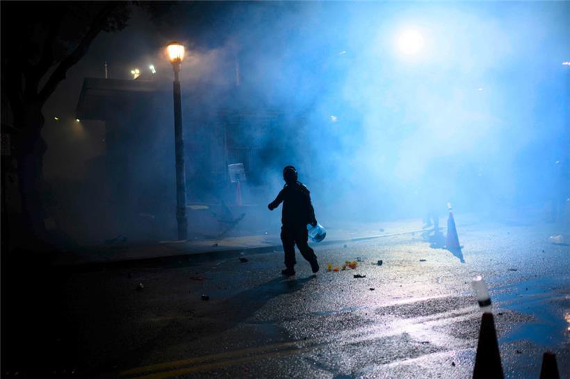 Ein Anti-I.C.E.-Demonstrant läuft am 18. Oktober 2025 in Portland, Oregon, durch eine Tränengaswolke in der Nähe des Gebäudes der US-Einwanderungs- und Zollbehörde
