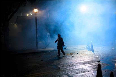 Ein Anti-I.C.E.-Demonstrant läuft am 18. Oktober 2025 in Portland, Oregon, durch eine Tränengaswolke in der Nähe des Gebäudes der US-Einwanderungs- und Zollbehörde
