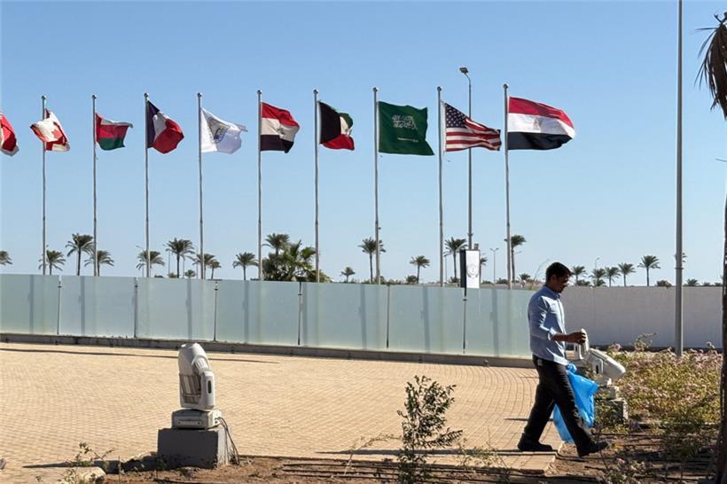 Ein Arbeiter geht an den Flaggen der teilnehmenden Länder auf einem von der ägyptischen Regierung veranstalteten Gipfel vorbei, um die Unterzeichnung des Waffenstillstandsabkommens zwischen Israel und der Hamas zu feiern
