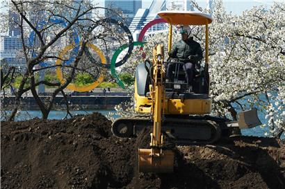 Ein Arbeiter sitzt in einem Bagger auf einem Erdhügel in der Nähe der Olympischen Ringe im Tokioter Stadtteil Odaiba.
