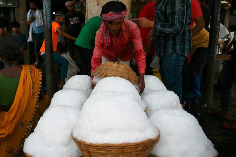 Ein Arbeiter transportiert an einem heißen Sommernachmittag auf einem Markt in Neu-Delhi Körbe mit Eis
