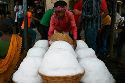 Ein Arbeiter transportiert an einem heißen Sommernachmittag auf einem Markt in Neu-Delhi Körbe mit Eis
