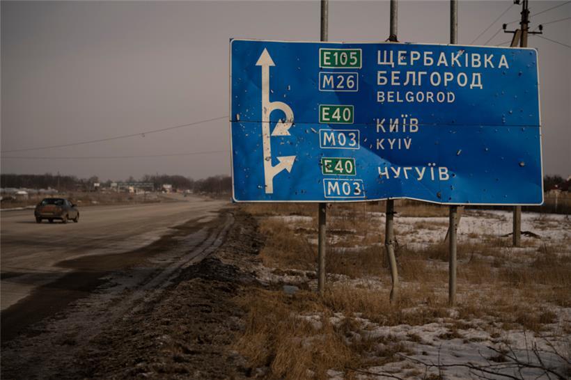 Ein Auto fährt an einem von Kugeln und Granatsplittern beschädigten Straßenschild auf der Straße zur russischen Stadt Belgorod vorbei. Das Foto ist vom 24. Februar 2023. 
