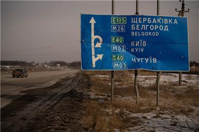 Ein Auto fährt an einem von Kugeln und Granatsplittern beschädigten Straßenschild auf der Straße zur russischen Stadt Belgorod vorbei. Das Foto ist vom 24. Februar 2023. 
