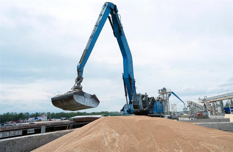 Ein Bagger verlädt in einem Getreidehafen Getreide in ein Frachtschiff
