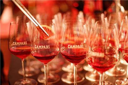 Ein Barkeeper gibt eine Blutorange in Campari-Gläser 
