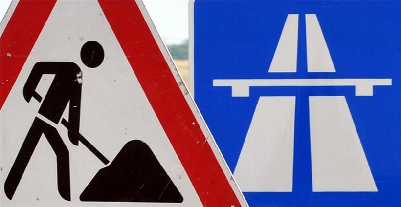 Ein Baustellenschild ist vor einem Autobahnschild platziert
