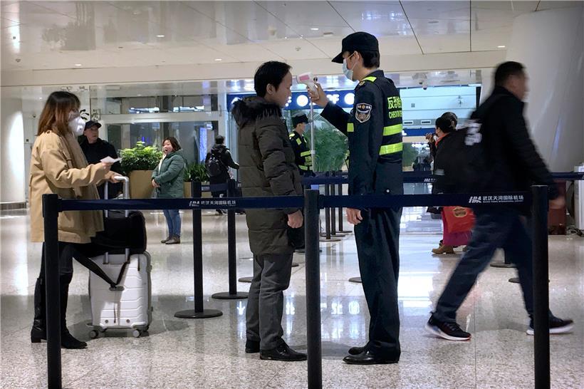 Ein Beamter misst mit einem Infrarot-Thermometer bei einem Reisenden im Flughafen Wuhan Tianhe International Airport Temperatur – als Schutzmaßnahme gegen die Verbreitung des Coronavirus
