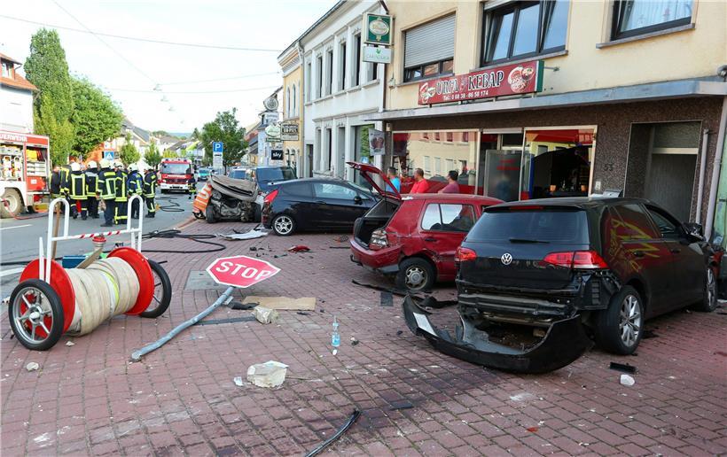 Ein Bild der Verwüstung bietet sich, nachdem ein Autofahrer ungebremst gegen einen Wagen (links hinten neben der Gruppe von Feuerwehrleuten) raste, in dem eine Frau und ein zwölfjähriges Kind dabei tödlich verletzt wurden
