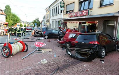 Ein Bild der Verwüstung bietet sich, nachdem ein Autofahrer ungebremst gegen einen Wagen (links hinten neben der Gruppe von Feuerwehrleuten) raste, in dem eine Frau und ein zwölfjähriges Kind dabei tödlich verletzt wurden
