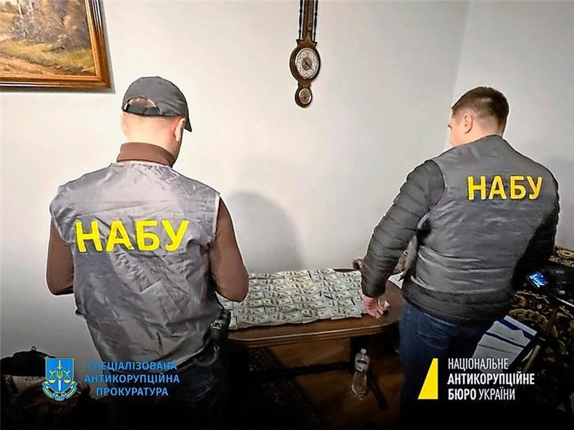 Ein Bild vom 23. Januar zeigt Mitglieder des nationalen Antikorruptionsbüros der Ukraine vor beschlagnahmten Geldscheinen
